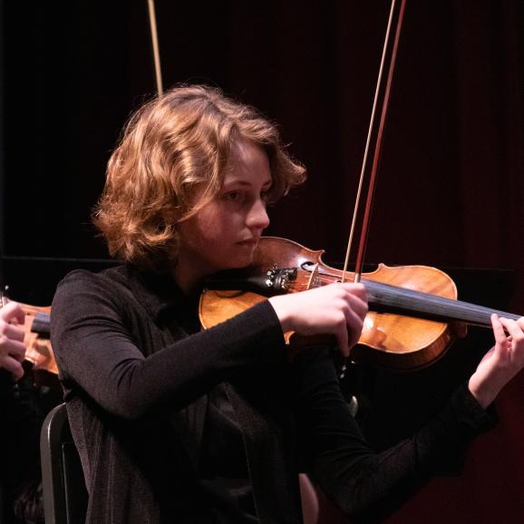 a woman plays violin in an orchestra