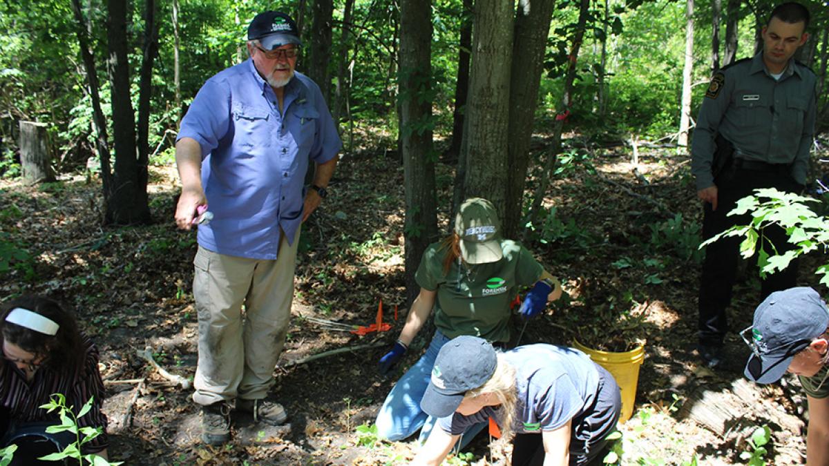 Dennis Dirkmaat teaching students forensic recovery methods in woods