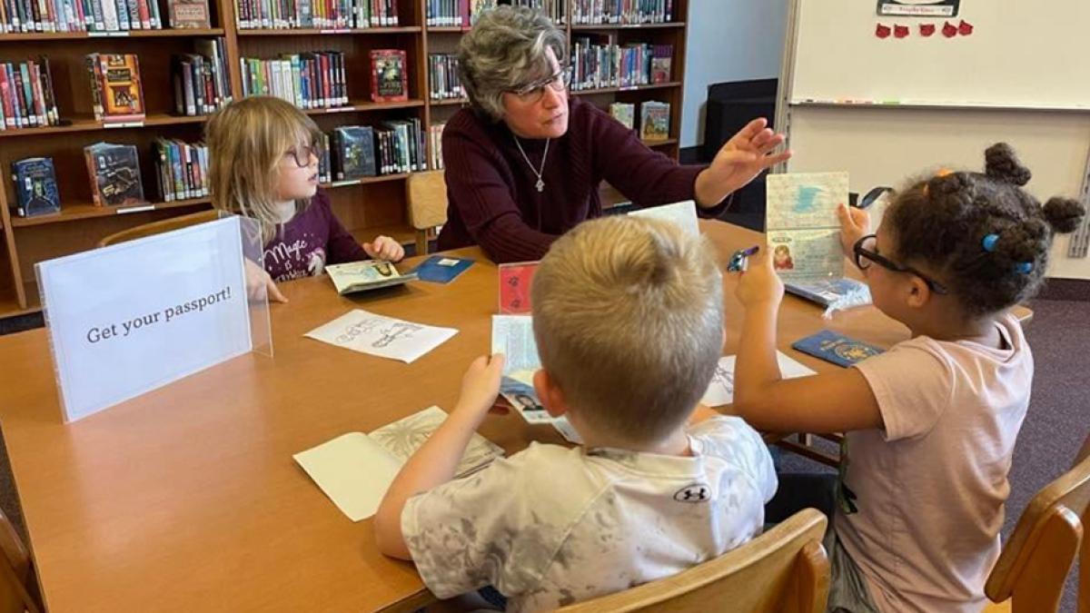 Professor Jann Haas sitting with children at a table