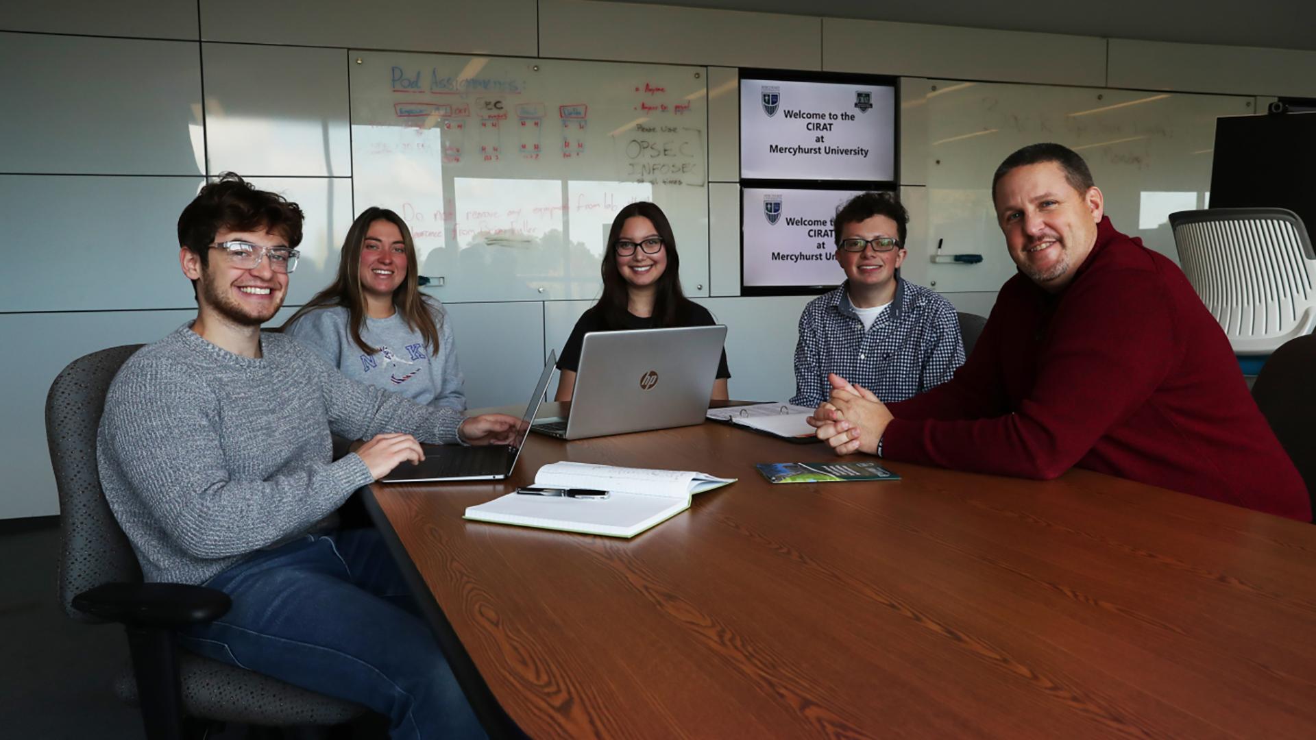 Dr. Brian Fuller and students sitting at table in the CIRAT lab, posing for a photo