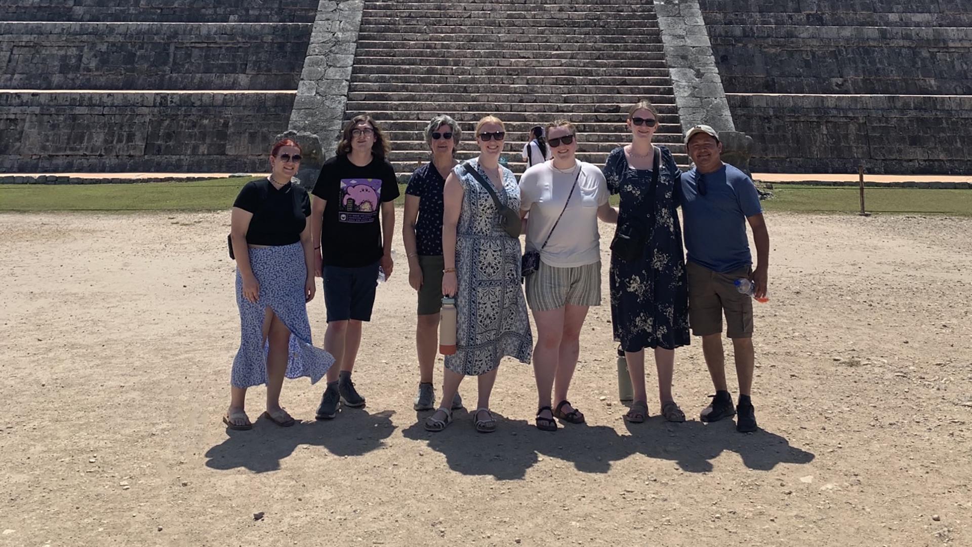 Faculty and students posing for a photo on a Spanish trip in front of El Castillo