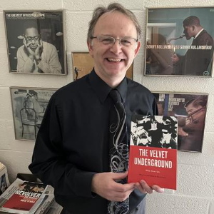 Dr. Roessner poses with a book called "The Velvet Underground"