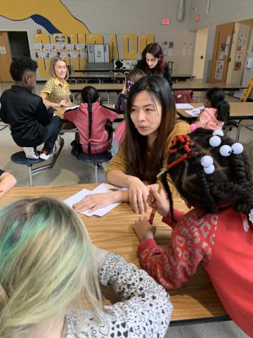 Asian Studies instructor teaching two female students the language while sitting down at a table