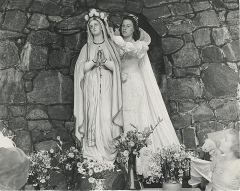 Female putting a flower crown on the Mary statue on May Day