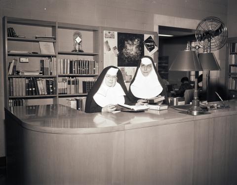 Sisters in Weber Hall, standing behind a desk