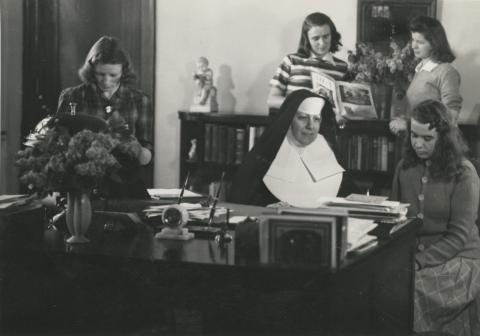 Sr. Mary Alice Weber working behind a desk in the registrar
