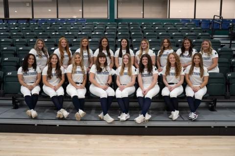 Team picture of the Mercyhurst women's softball team, sitting on gym bleachers