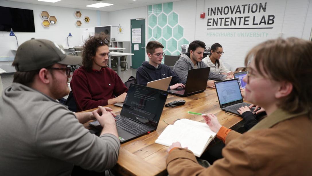 Students working at a table on computers in the Innovation Entente Lab