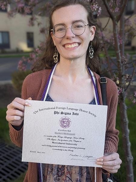 Student holding up a Phi Sigma Iota International Foreign Language Honor Society certification